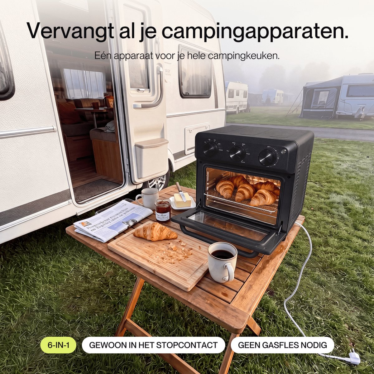 A black oven on a wooden table outside a caravan, with croissants and mugs of coffee on the table.