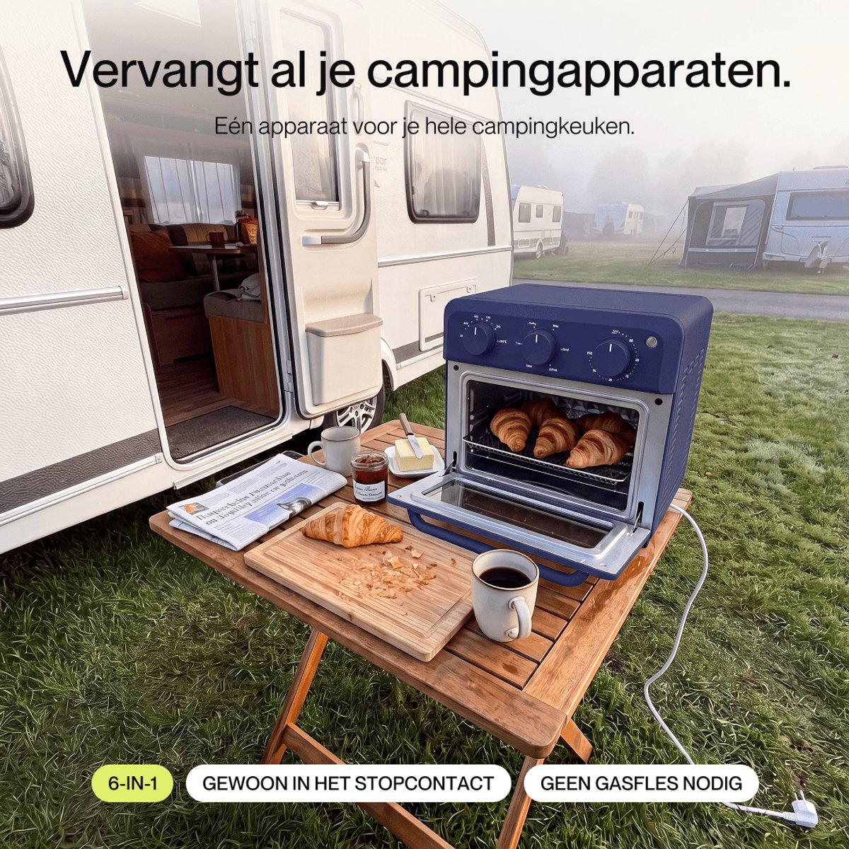 A blue mini oven on a wooden table outside a camper, with croissants, coffee, and breakfast items.