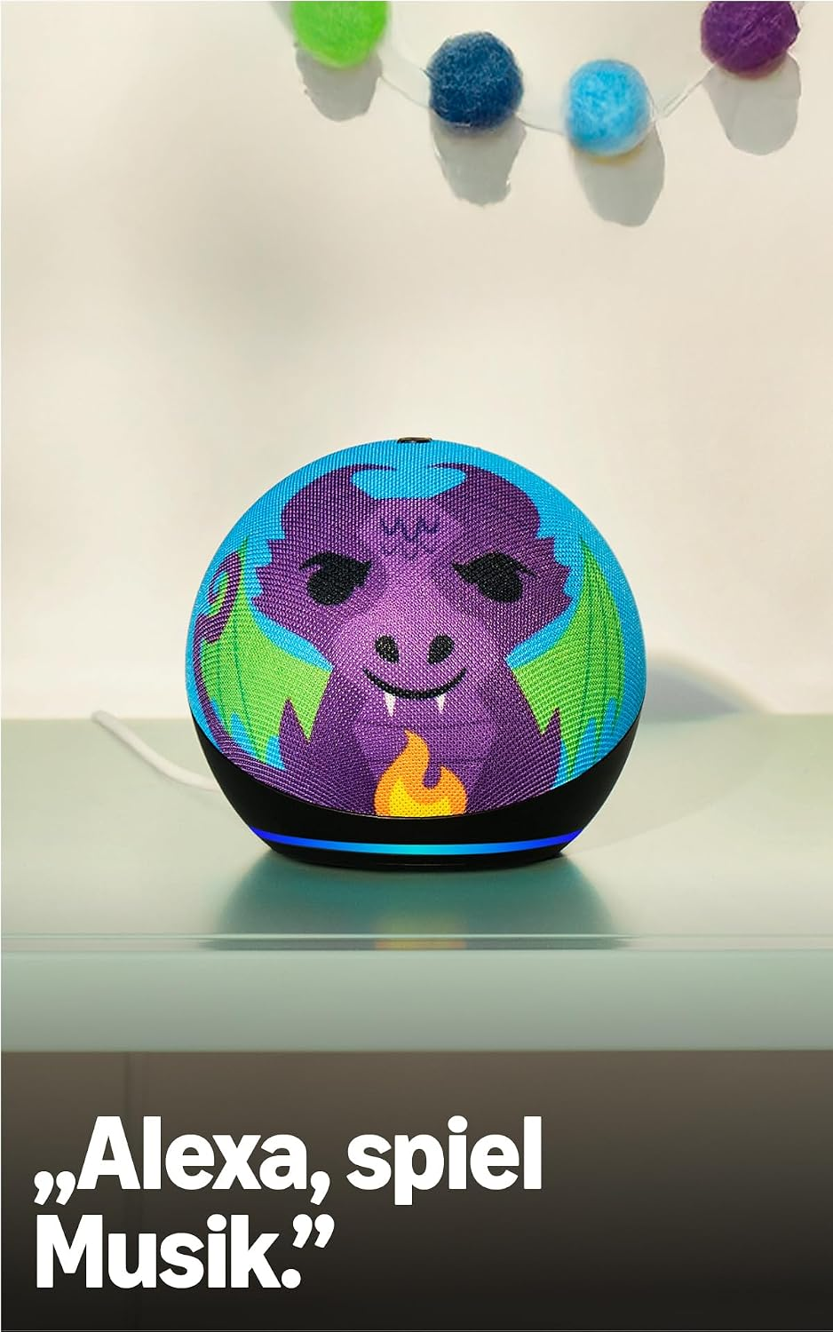 Ein runder blauer Smart-Lautsprecher mit Drachenmotiv und bunten Filzkugeln im Hintergrund.