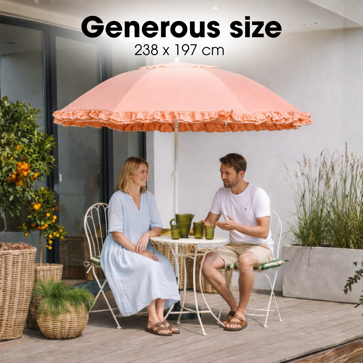 A man and woman sit at a small patio table under a large peach-colored parasol.