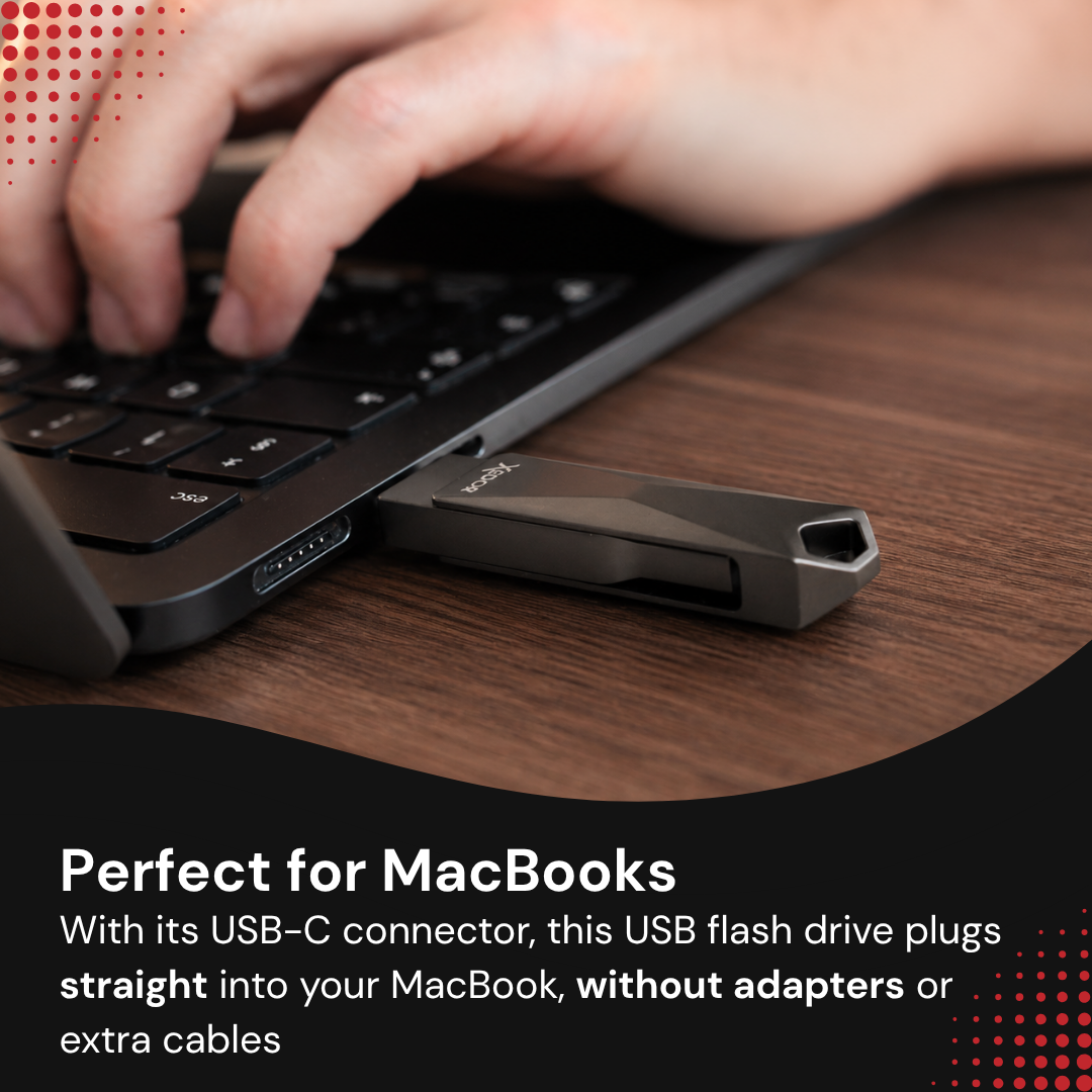 A black USB flash drive is plugged into a laptop on a wooden desk, while a hand types on the keyboard.