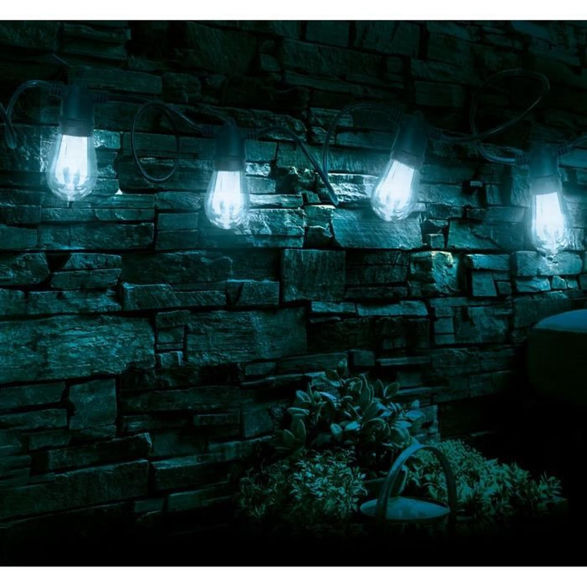 Eine Lichterkette mit blau leuchtenden Edison-Glühbirnen hängt nachts vor einer dunklen Steinwand.