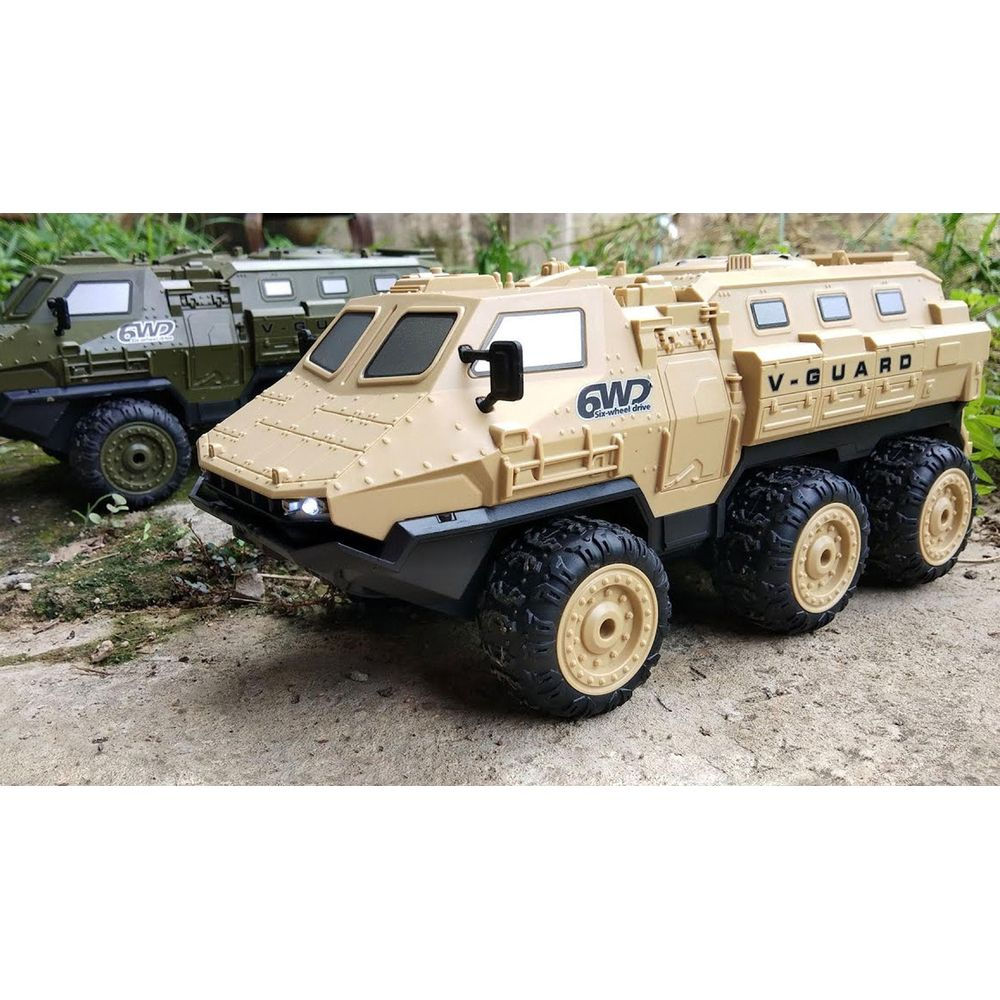 Ein beiger und ein grüner sechsrädriger Spielzeug-Militärlastwagen stehen draußen auf Beton.