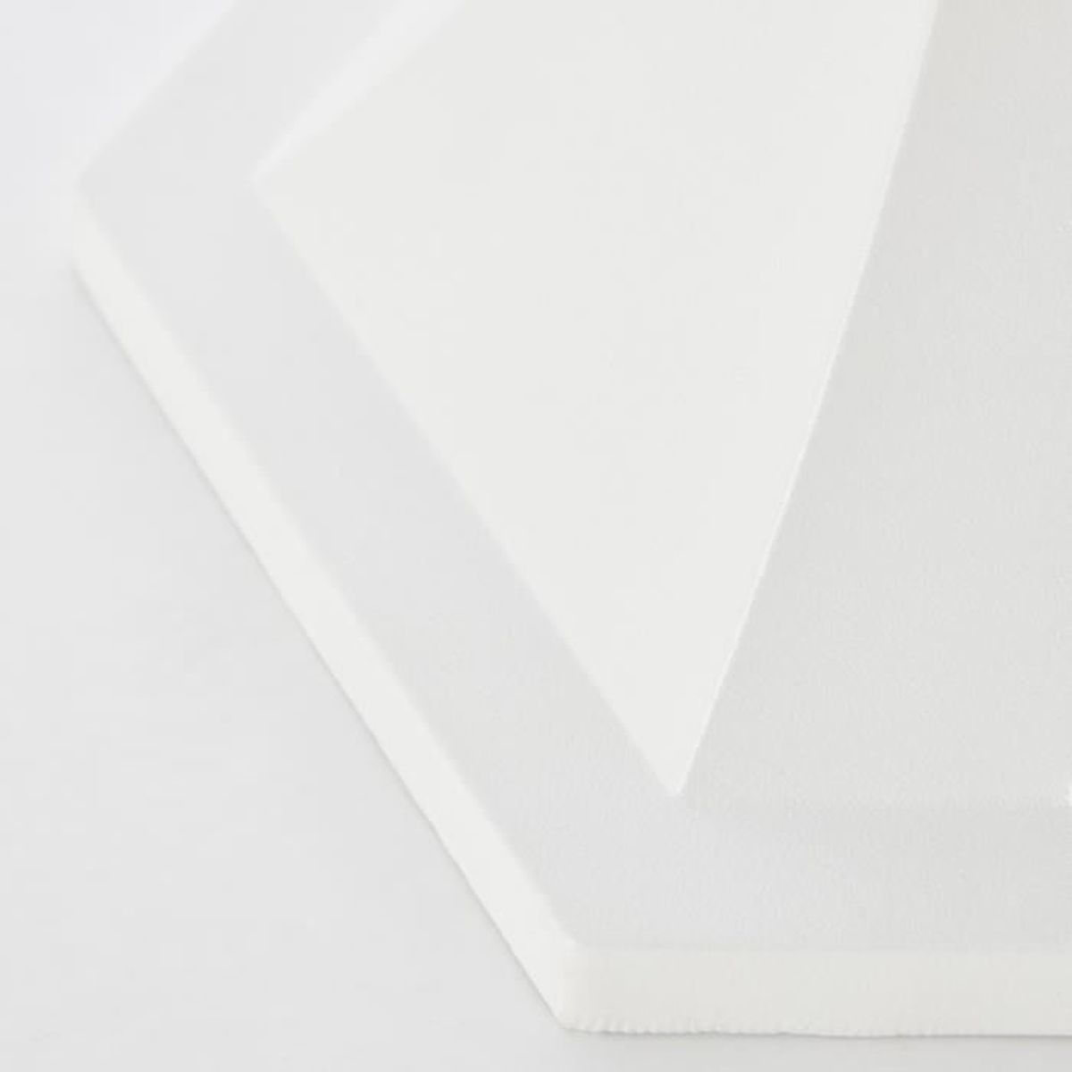 Eine weiße, dreidimensionale geometrische Fliese mit abgeschrägten Kanten vor einem weißen Hintergrund.