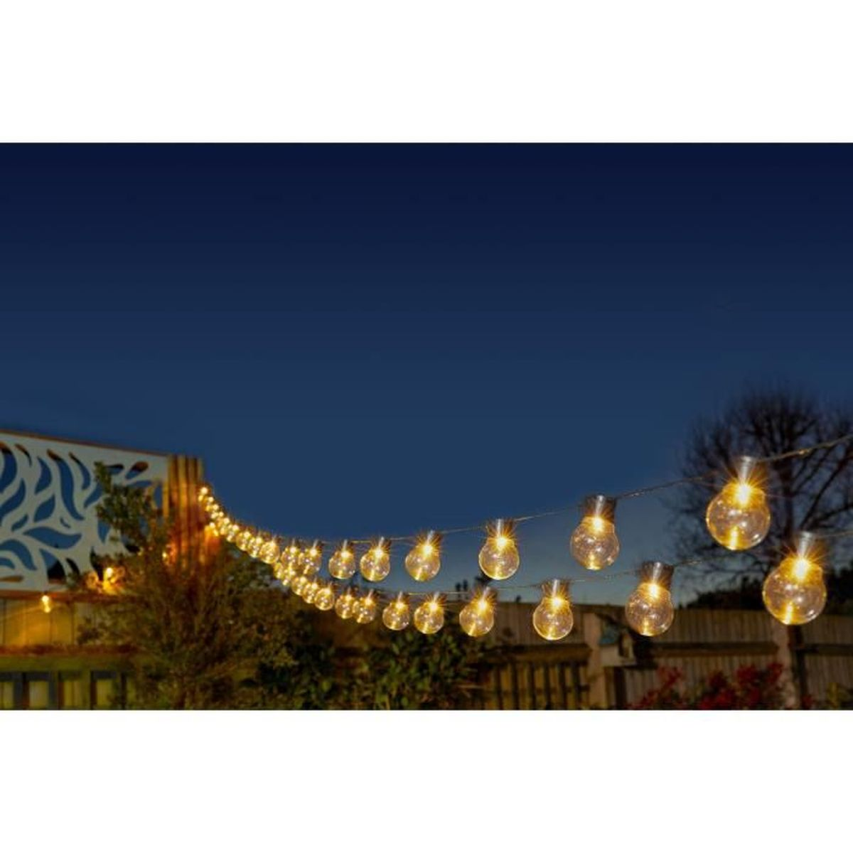 Lichterketten hängen im nächtlichen Garten mit warmen Glühbirnen.