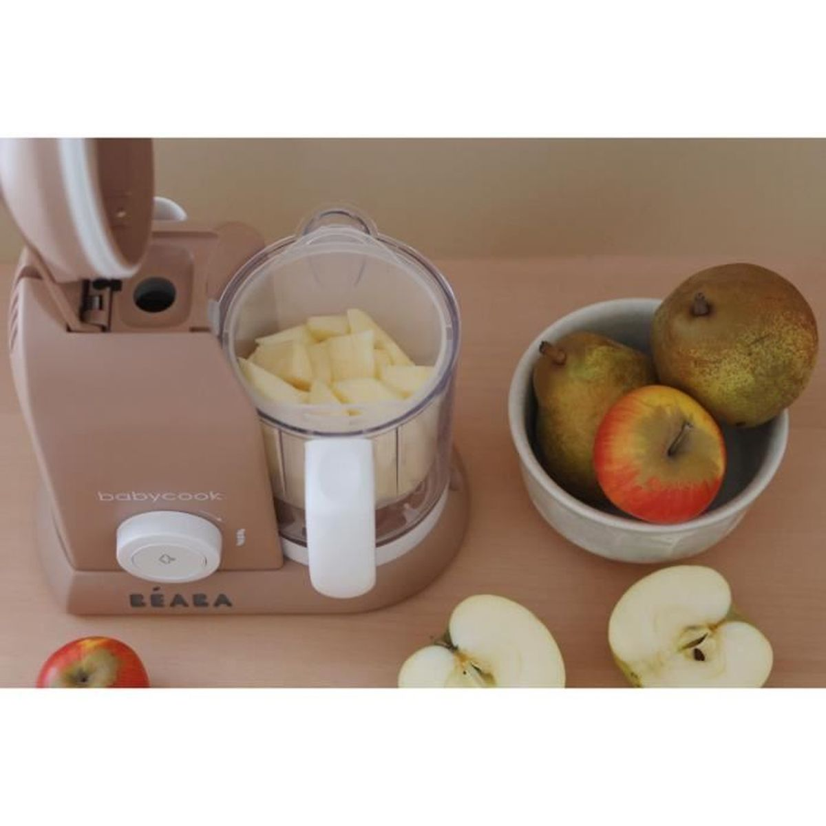 Ein rosafarbener Beaba Babycook mit geschnittenem Obst und Früchten in einer Schüssel daneben.