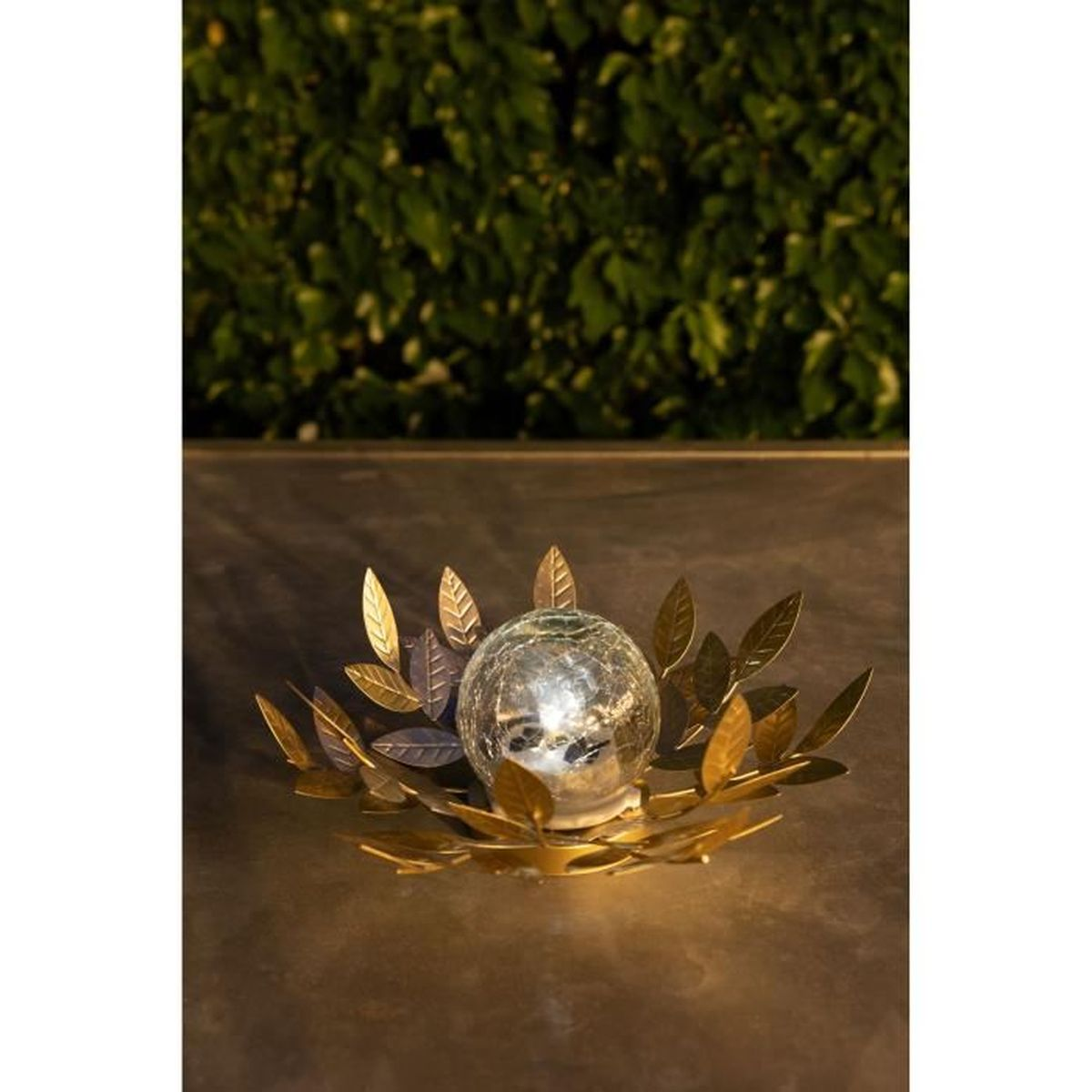 Eine glühende Glaskugel umgeben von goldenen Metallblättern auf einem dunklen Tisch.