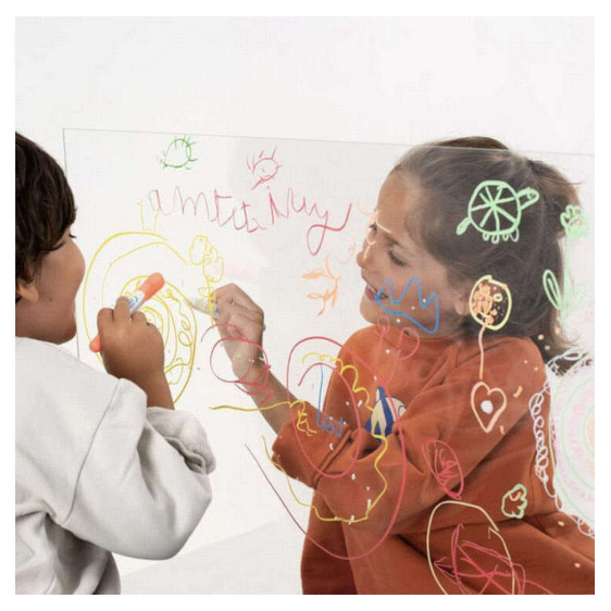 Zwei Kinder malen mit bunten Stiften auf eine transparente Acryltafel.