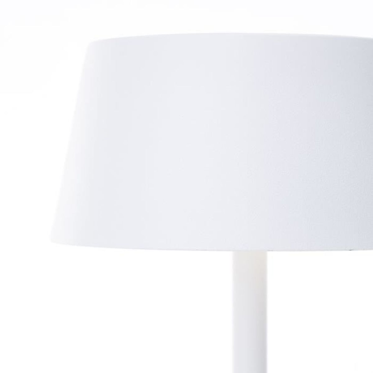 Eine weiße zylindrische Tischlampe mit einfachem Lampenschirm auf weißem Hintergrund.