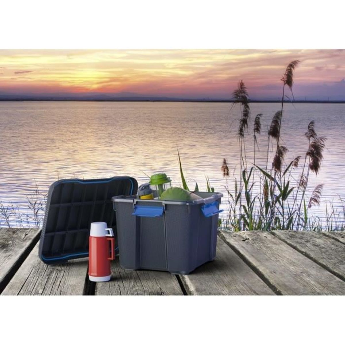 Eine graue Aufbewahrungsbox und eine rote Thermoskanne stehen auf einem Holzsteg am See bei Sonnenuntergang.