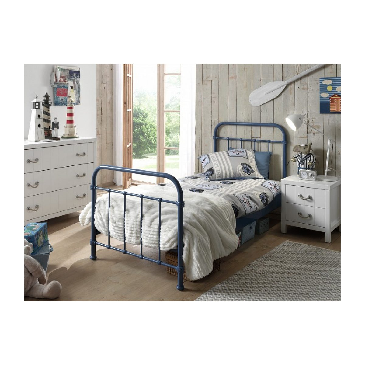 Blaues Metallbett mit weißem Plaid, Nachttisch und Kommode in einem kinderzimmer im maritimen Stil.