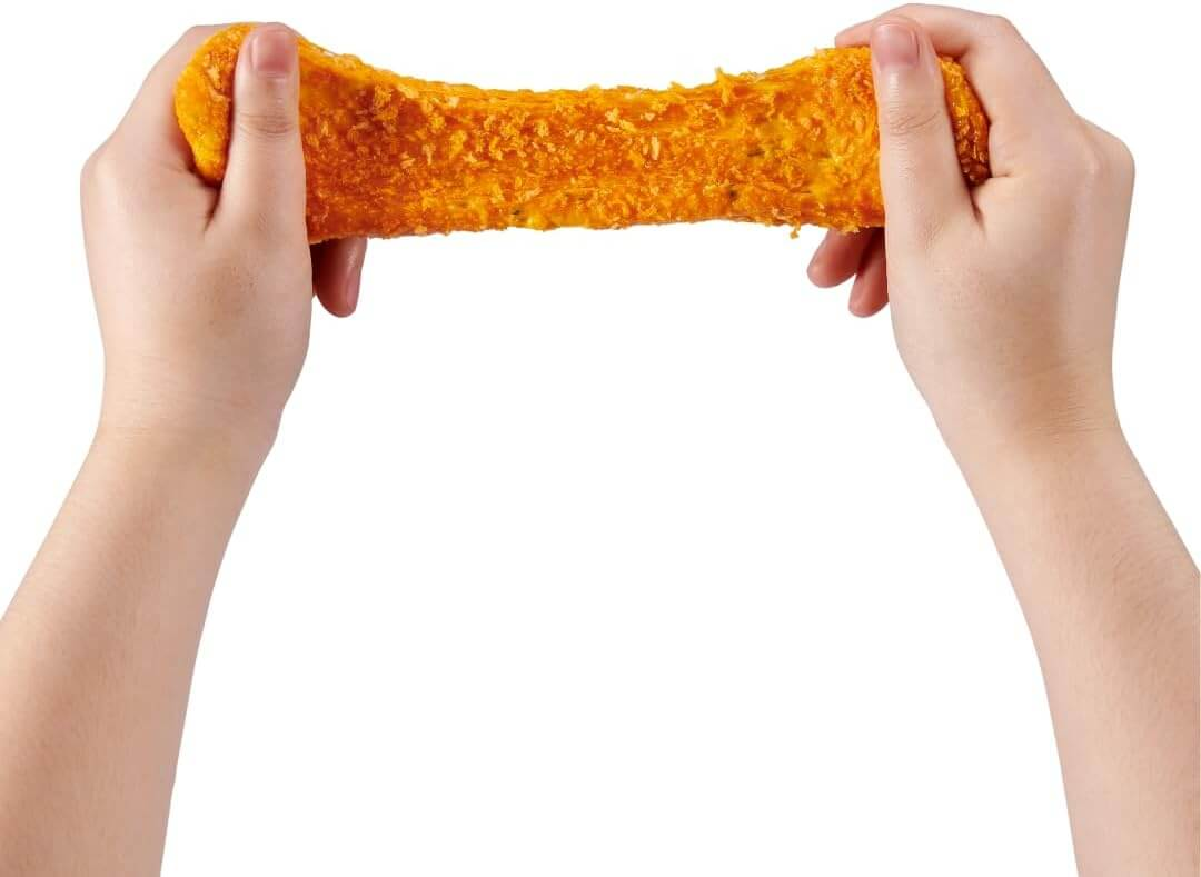 Zwei Hände ziehen an einer panierten, orangefarbenen Speise, die klebrig und dehnbar ist, auf weißem Hintergrund.