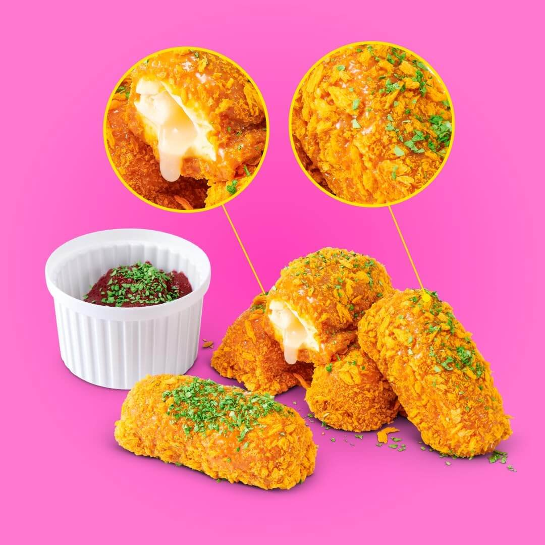 Goldbraun frittierte Käseriegel mit Kräutern neben einer weißen Schüssel mit roter Soße vor rosa Hintergrund.
