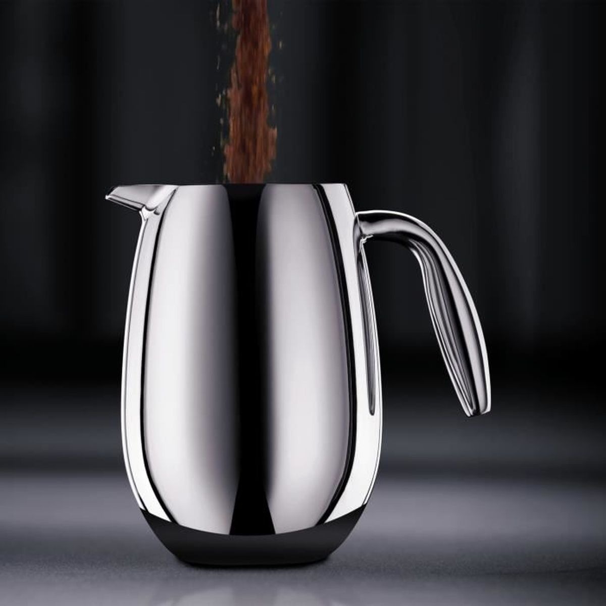 Kaffeepulver wird in eine glänzende silberne Kaffeekanne auf einem dunklen Tisch geschüttet.