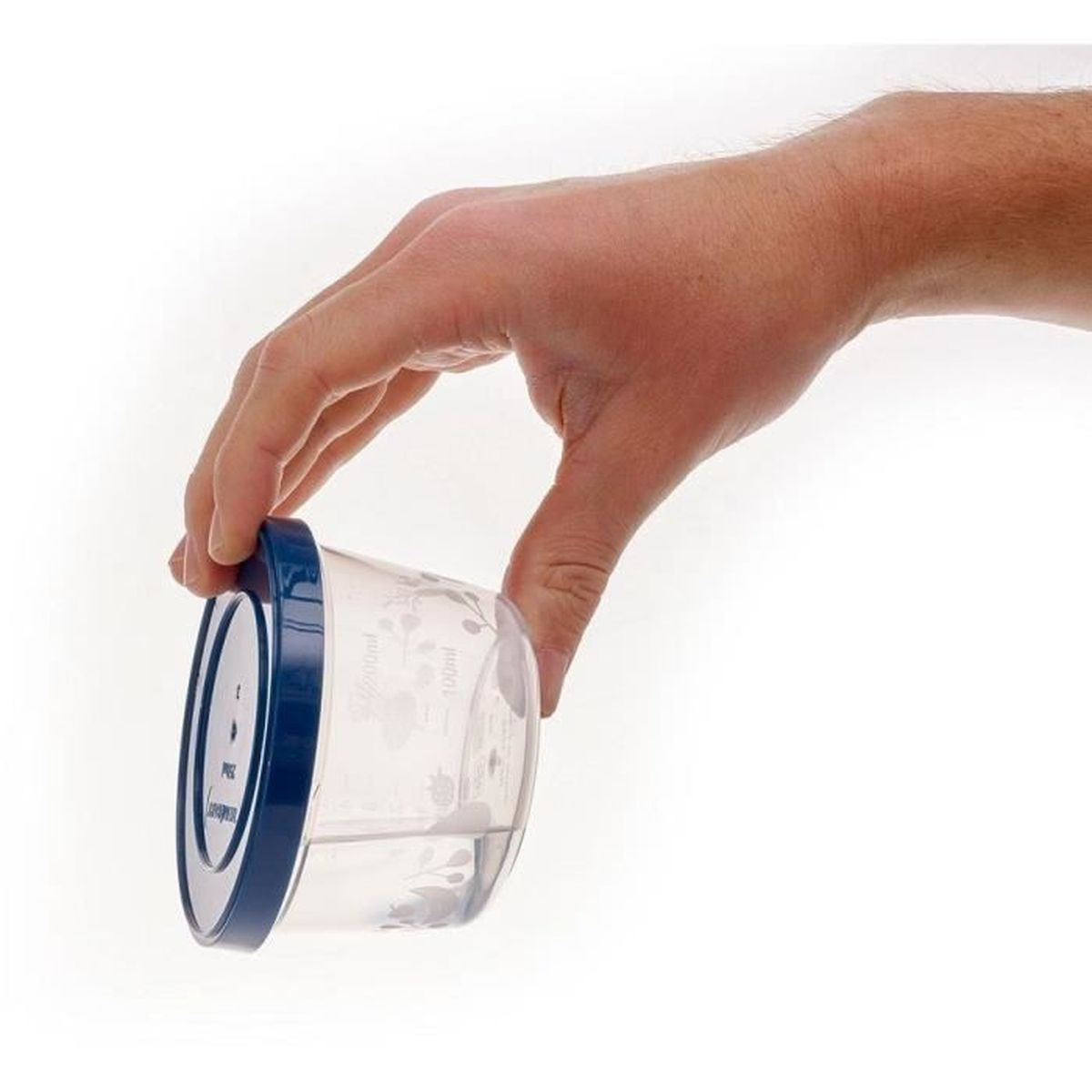 Eine Hand hält einen kleinen, transparenten Plastikbecher mit blauem Deckel vor weißem Hintergrund.