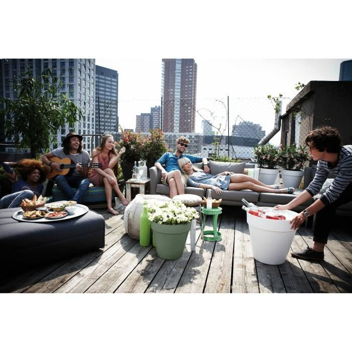Freunde feiern eine Dachterrassenparty mit Musik, Getränken und Blick auf die Skyline der Stadt.