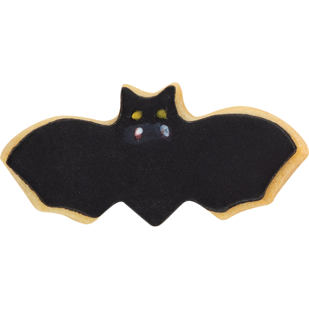 Ein Fledermaus-Keks mit schwarzer Glasur, gelben Augen und kleinen weißen Fangzähnen auf weißem Hintergrund.