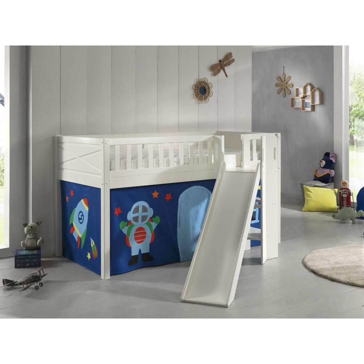 Weißes Kinder-Hochbett mit weißer Rutsche, blauem Weltall-Spielzeltvorhang und Spielzeug.