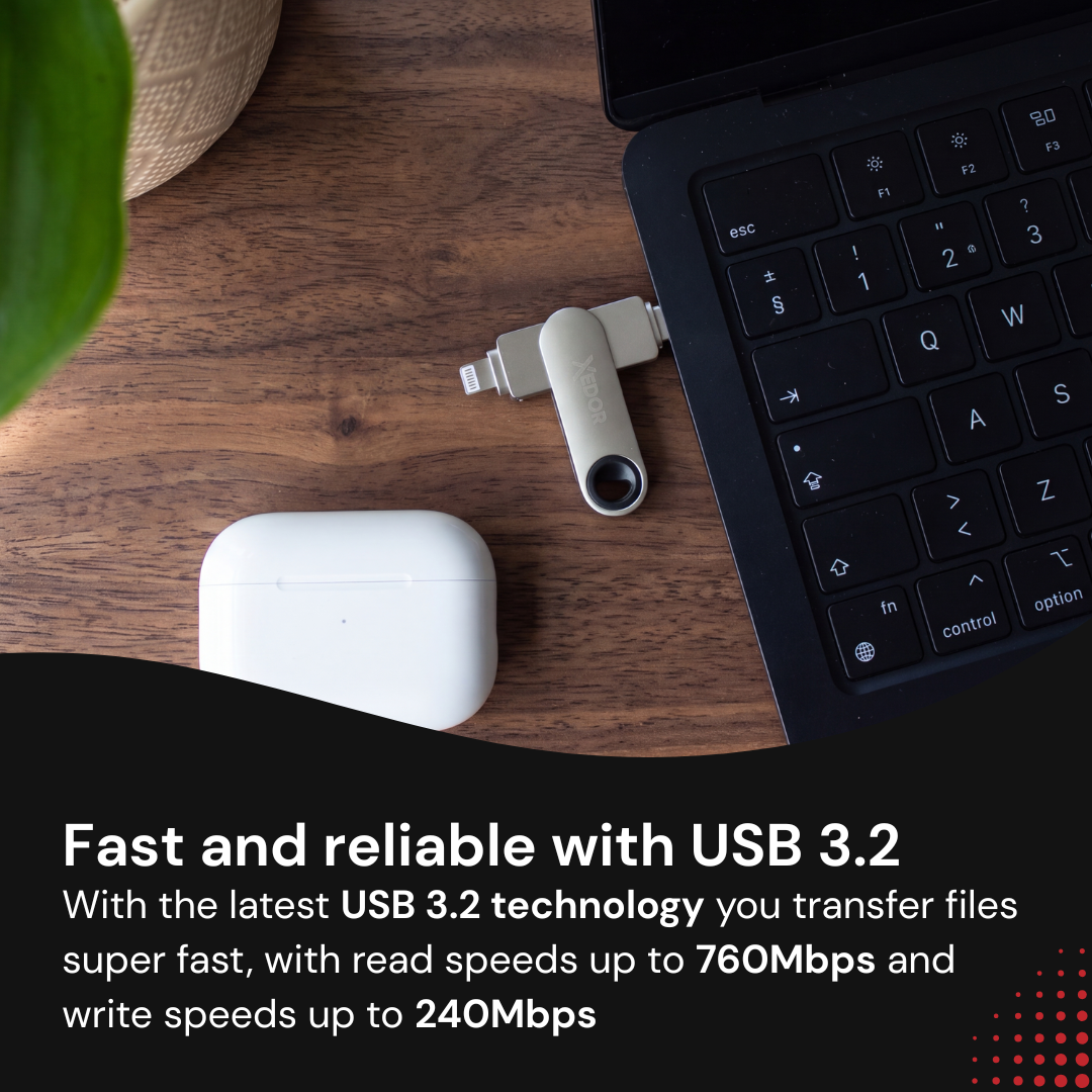 Srebrny pendrive podłączony do laptopa obok białego etui ładującego na drewnianym stole.