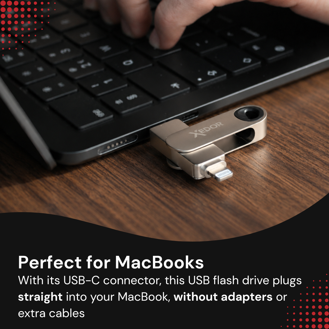 Srebrna pamięć USB leży na drewnianym biurku przed laptopem, podczas gdy ktoś pisze.