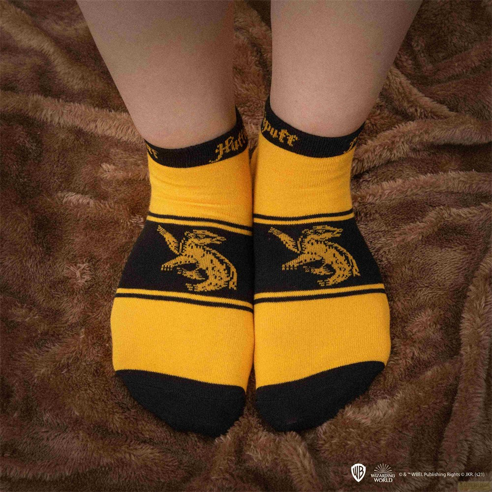 Persona con calcetines amarillos y negros de Hufflepuff sobre una manta marrón.