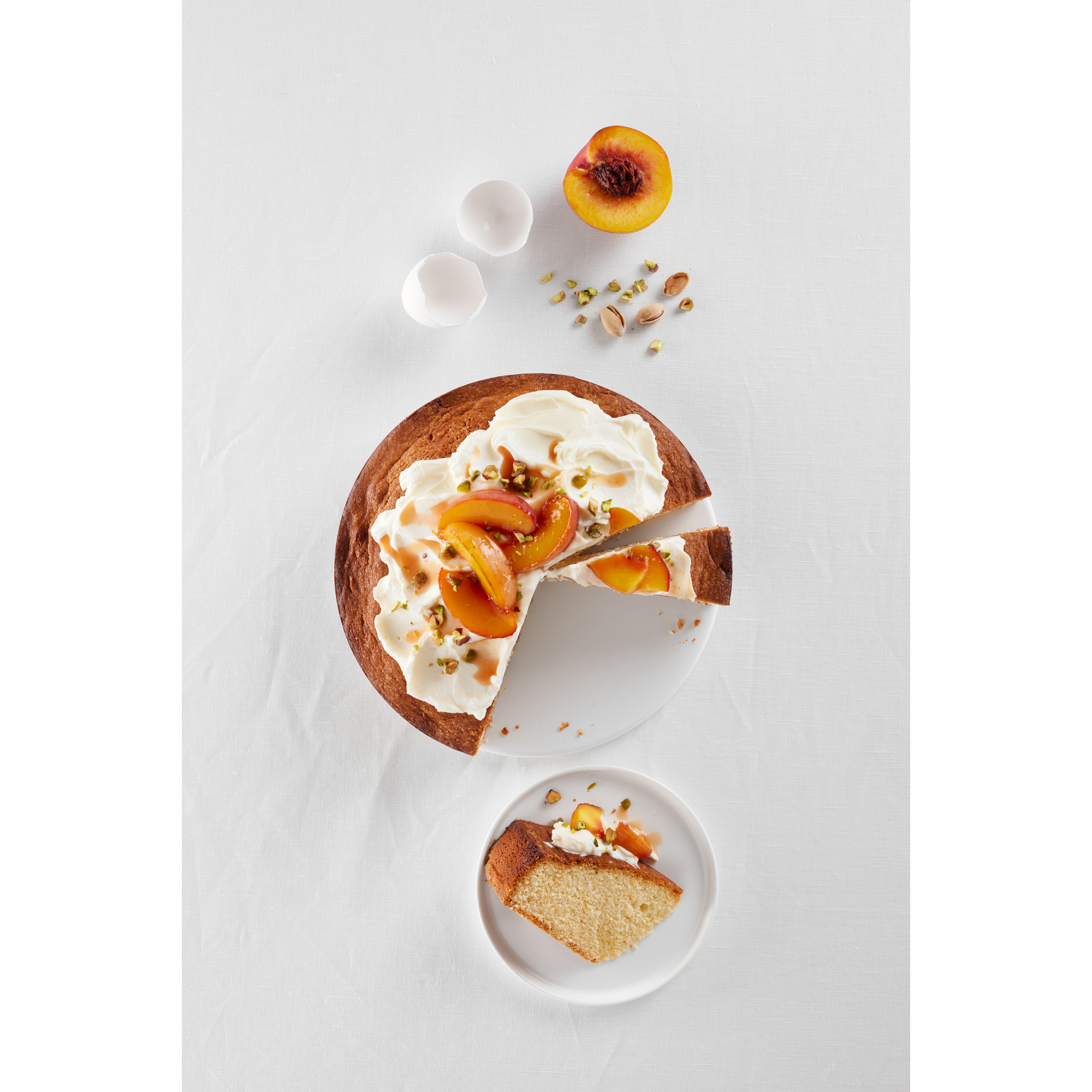 Pfannkuchen mit Sahne, Pfirsichen und Pistazien auf weißem Grund.