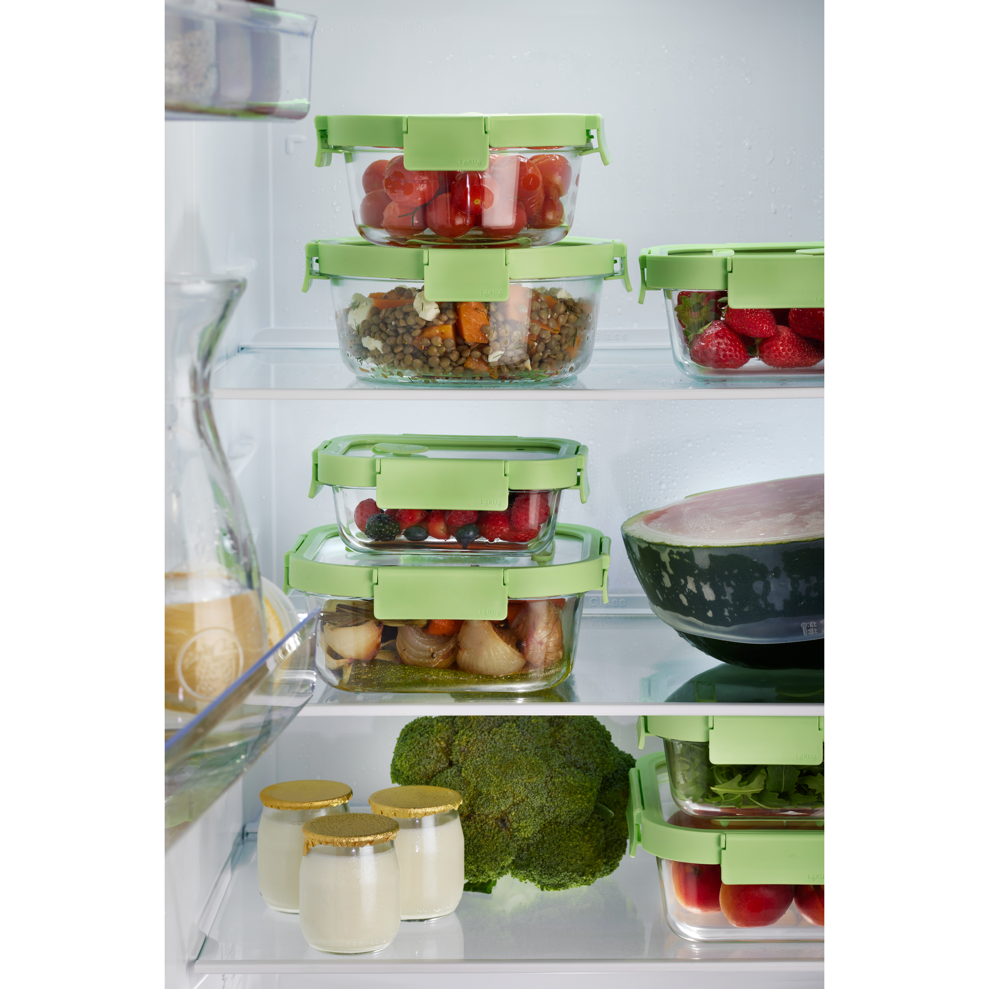 Ein gut gefüllter Kühlschrank mit Glasbehältern voller Gemüse, Früchte, Joghurt und einer halben Wassermelone.