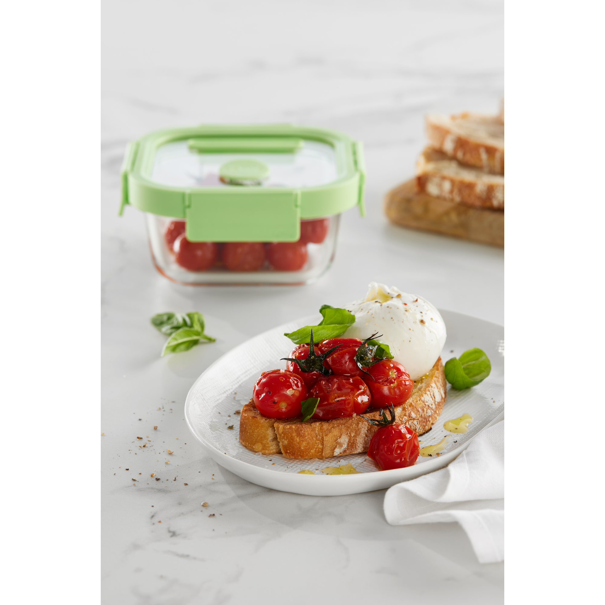 Geröstetes Brot mit gebratenen Tomaten, Mozzarella und Basilikum auf einem Teller.