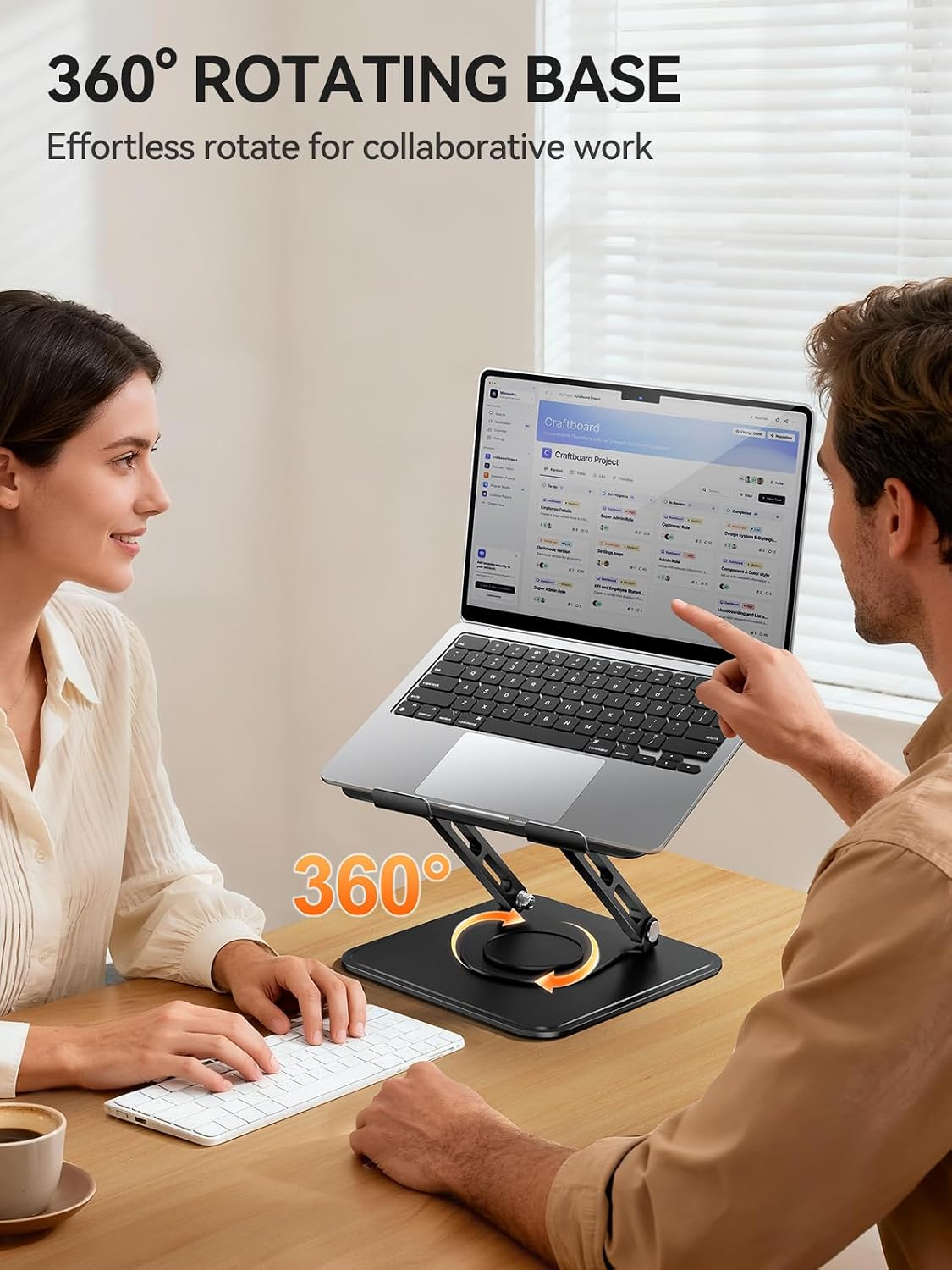 Dos personas colaboran alrededor de una laptop en un soporte giratorio en un escritorio.