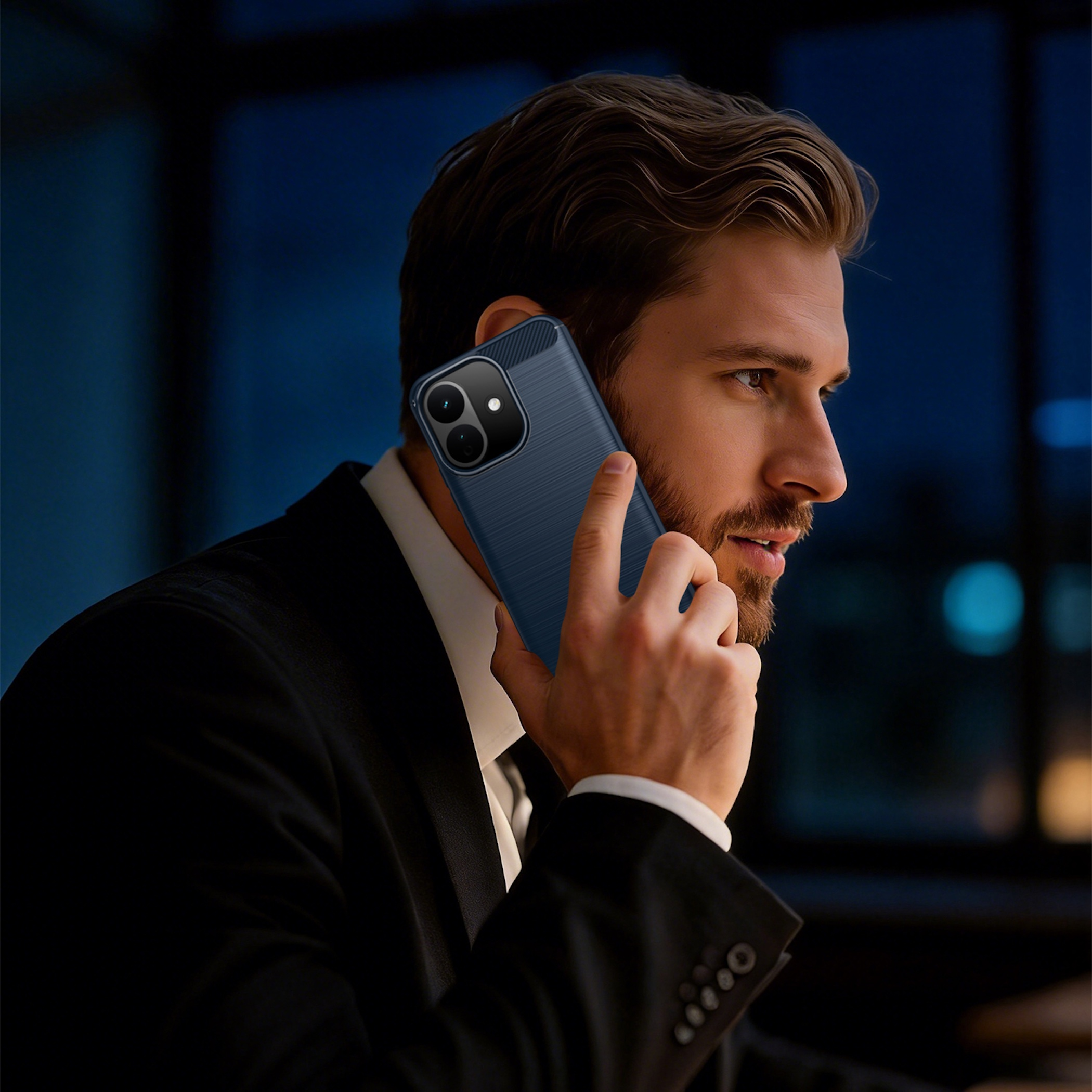 Ein Mann im Anzug telefoniert in einem dunklen Raum mit seinem blauen Smartphone.