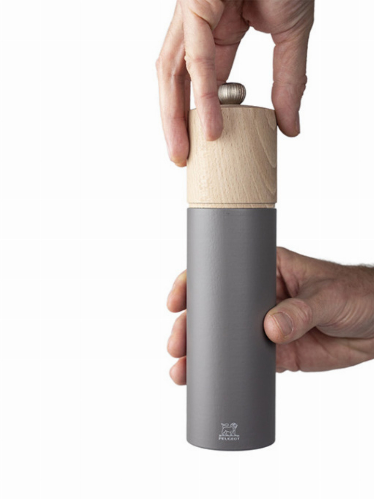 Hände halten eine hölzerne und graue Pfeffermühle vor weißem Hintergrund.
