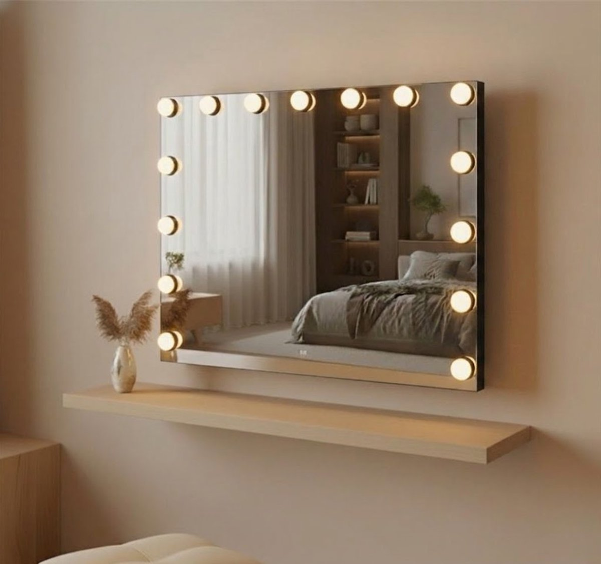A lighted vanity mirror hangs on a wall above a wooden shelf, reflecting a bedroom with a bed and a bookshelf.