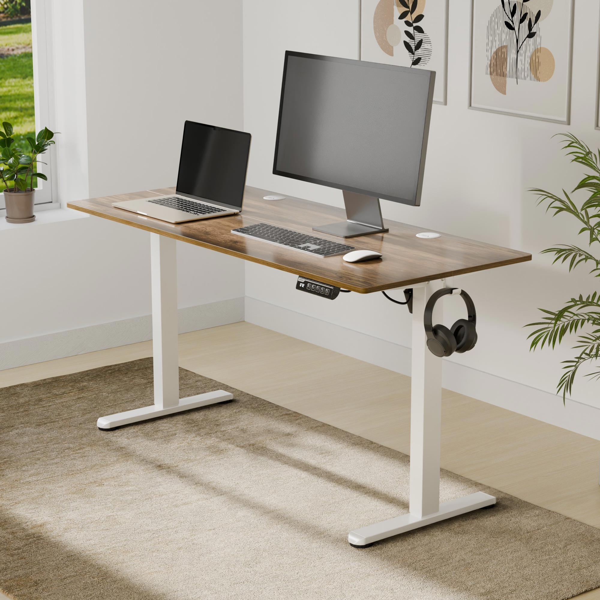 Ein höhenverstellbarer Schreibtisch mit Holzplatte, Laptop, Monitor und Kopfhörern in einem hellen Raum.