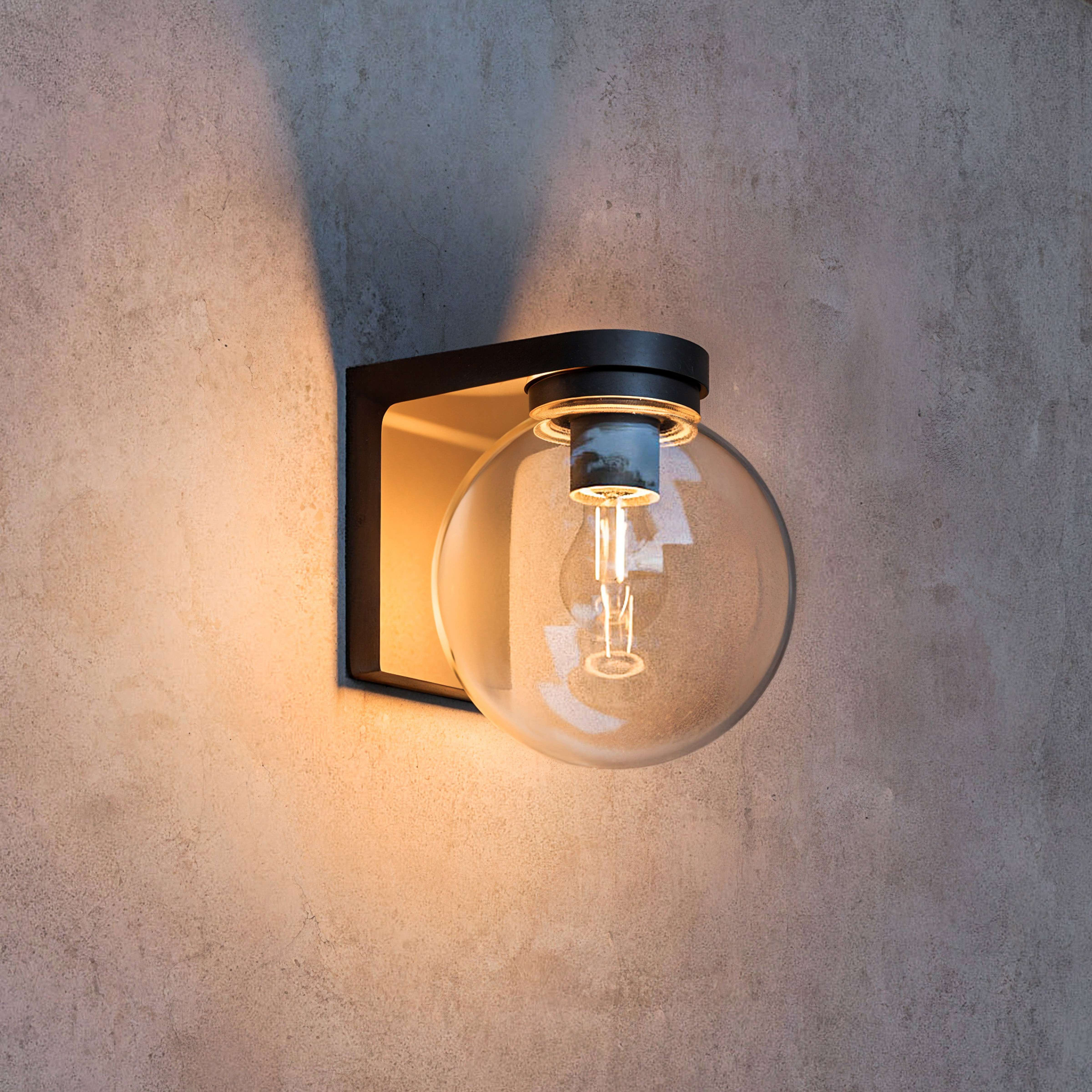 Een moderne zwarte wandlamp met een glazen bol lamp op een grijze muur.
