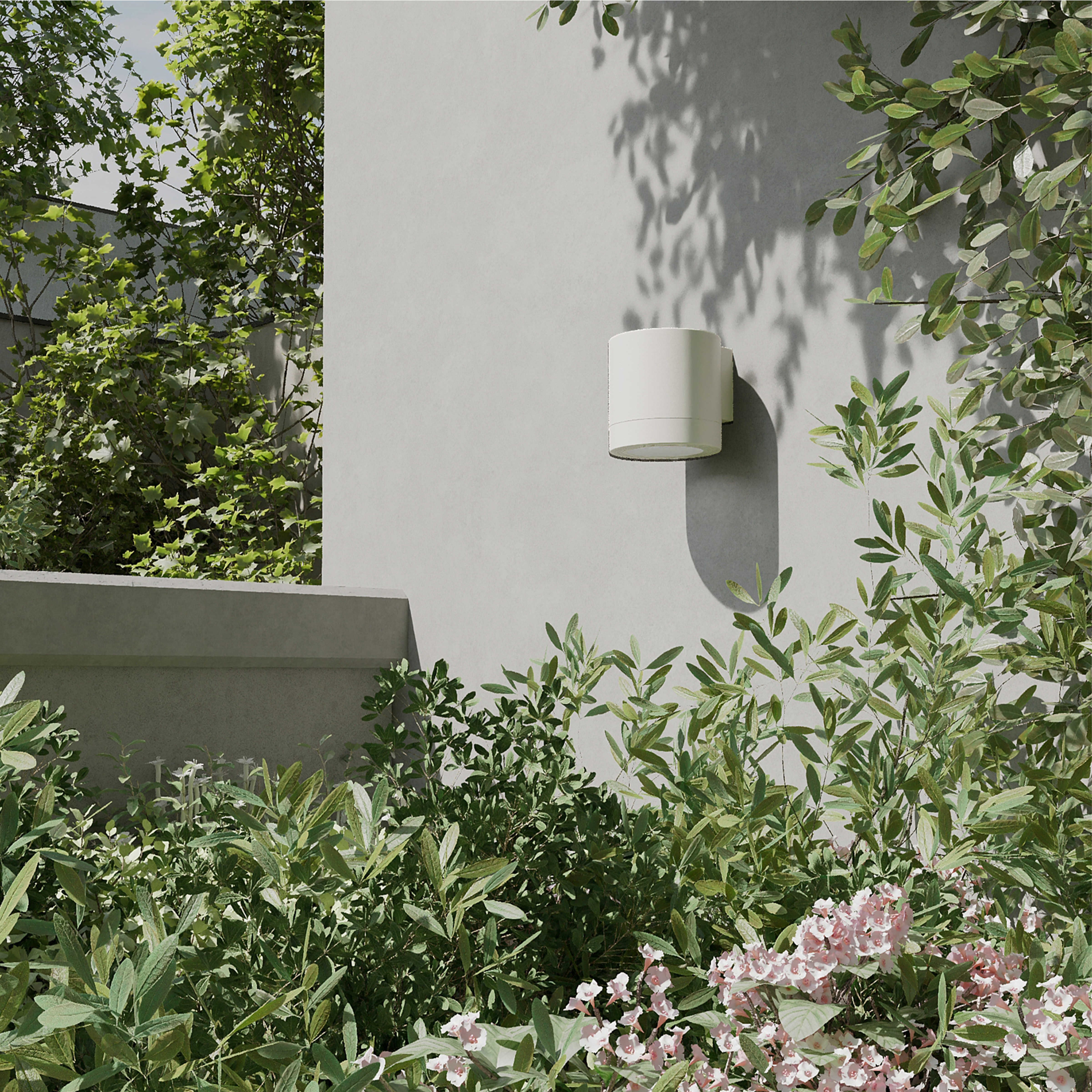 Een ronde witte buitenmuurlamp op een grijze muur, omringd door groen loof.
