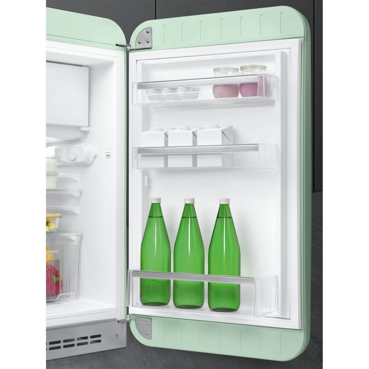Frigorífico verde pastel abierto con botellas y recipientes en los estantes de la puerta.