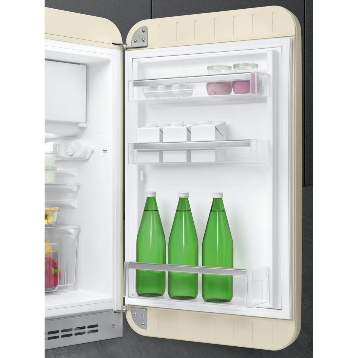 Refrigerador beige abierto con botellas de vidrio verde y alimentos en los estantes de la puerta.