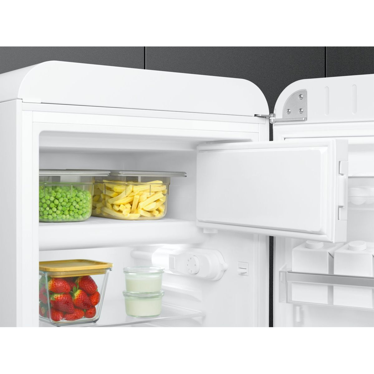Un refrigerador blanco abierto muestra estantes con alimentos frescos en recipientes de vidrio.