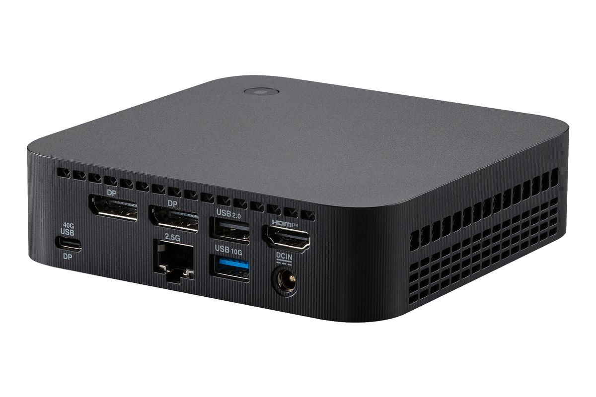 Mini PC negro con puertos traseros que incluyen USB, HDMI y DisplayPort sobre fondo blanco.