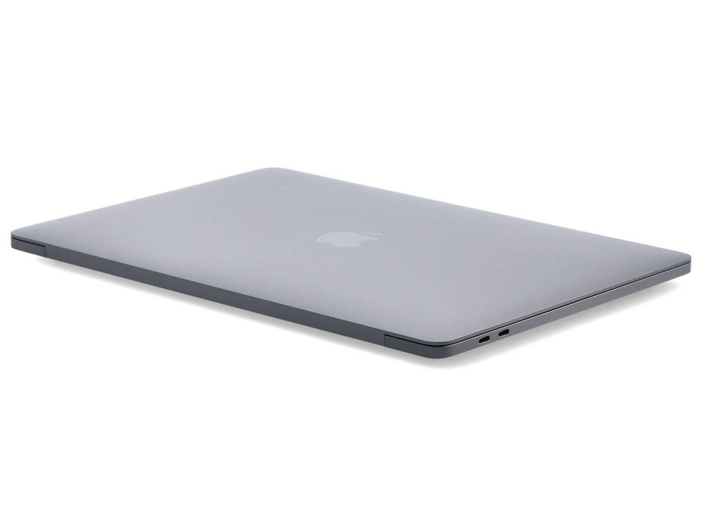 Zamknięty szary MacBook spoczywa na białej powierzchni z widocznymi portami USB-C.