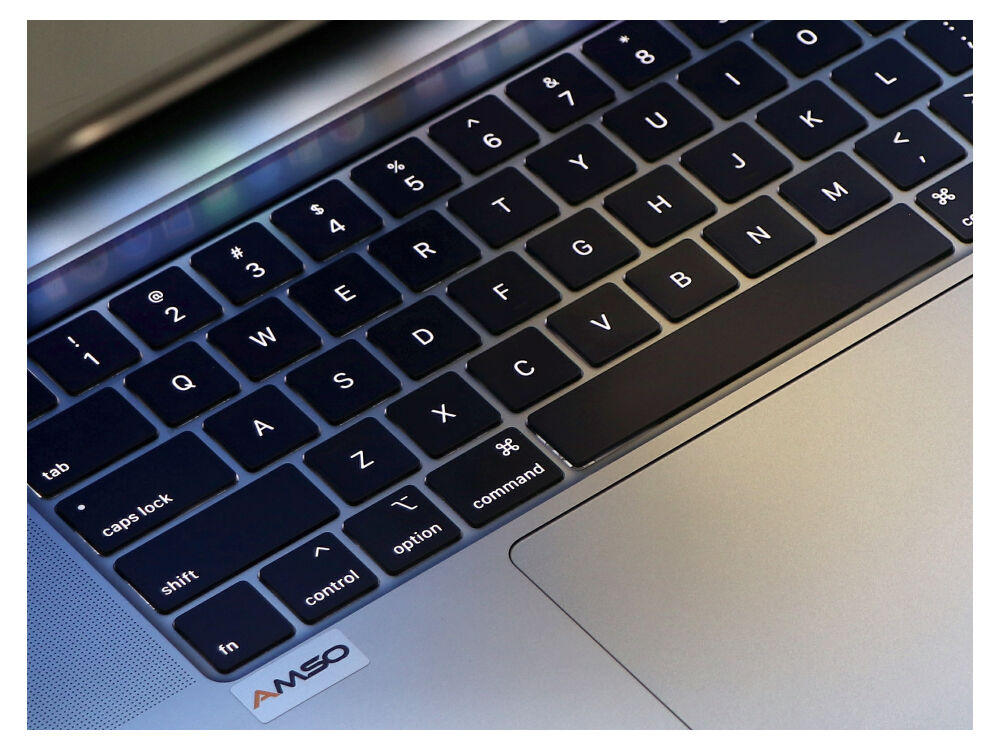 Zbliżenie podświetlanej klawiatury laptopa z układem QWERTY i srebrną obudową.