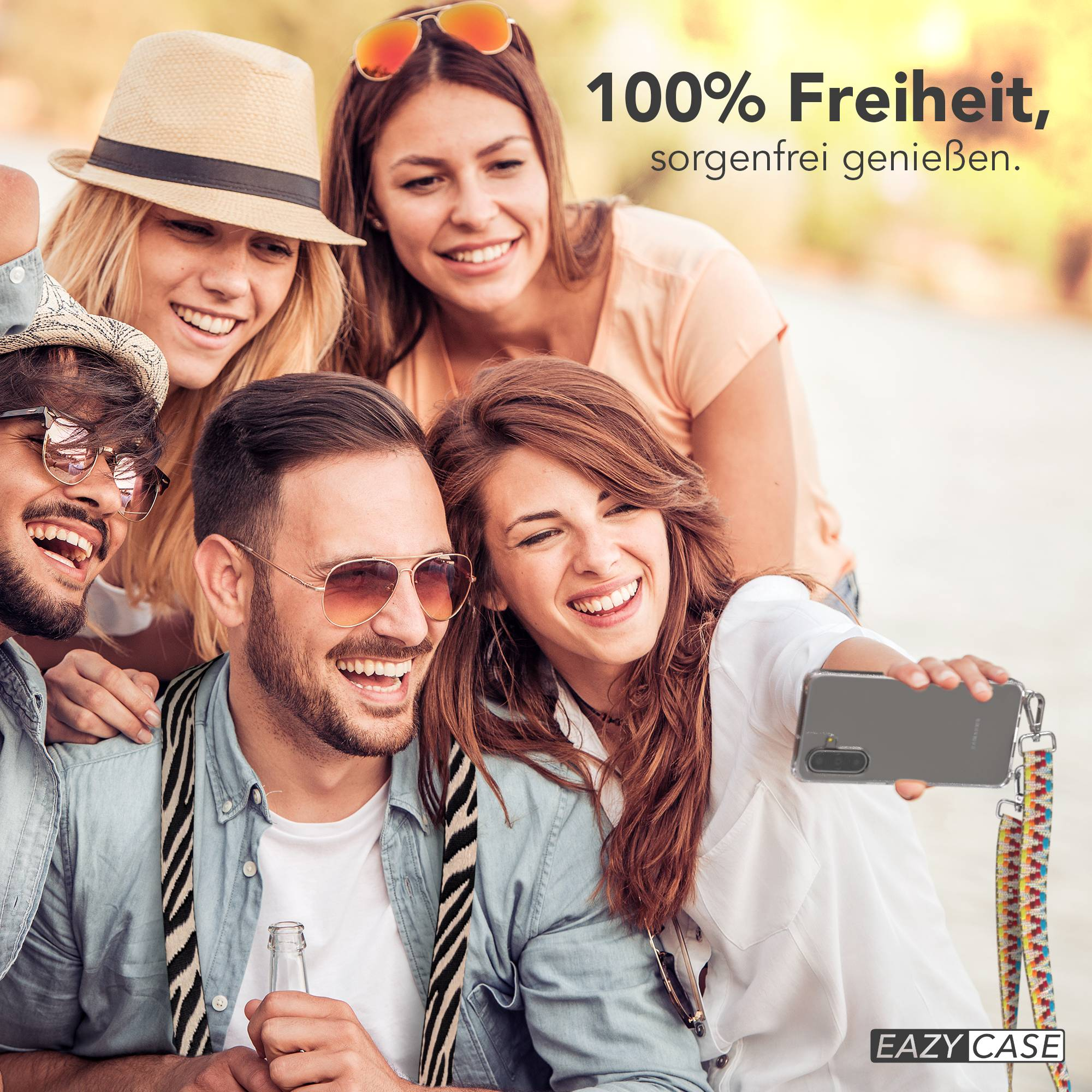 Vier glückliche Freunde machen draußen ein Selfie mit einem Smartphone an einem bunten Umhängeband.
