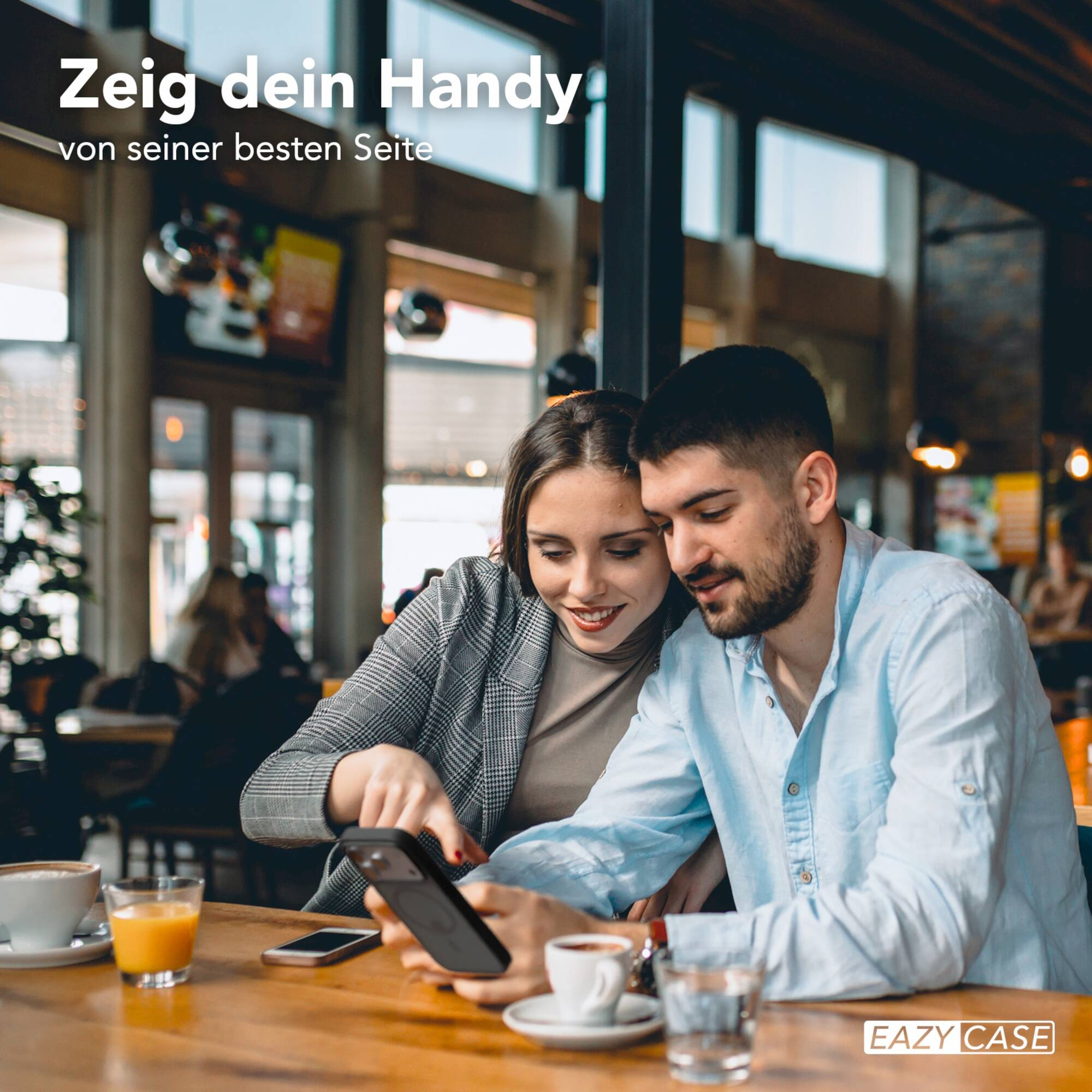 Ein Paar sitzt in einem Café, schaut auf ein Smartphone und trinkt Kaffee.