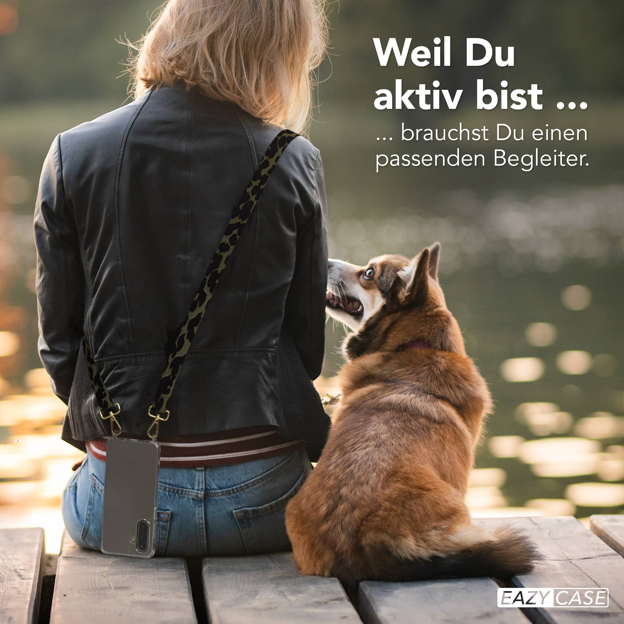 Eine Frau mit Lederjacke und ein Hund sitzen am Steg. Ein Smartphone mit Leo-Gurt hängt an ihrer Seite.