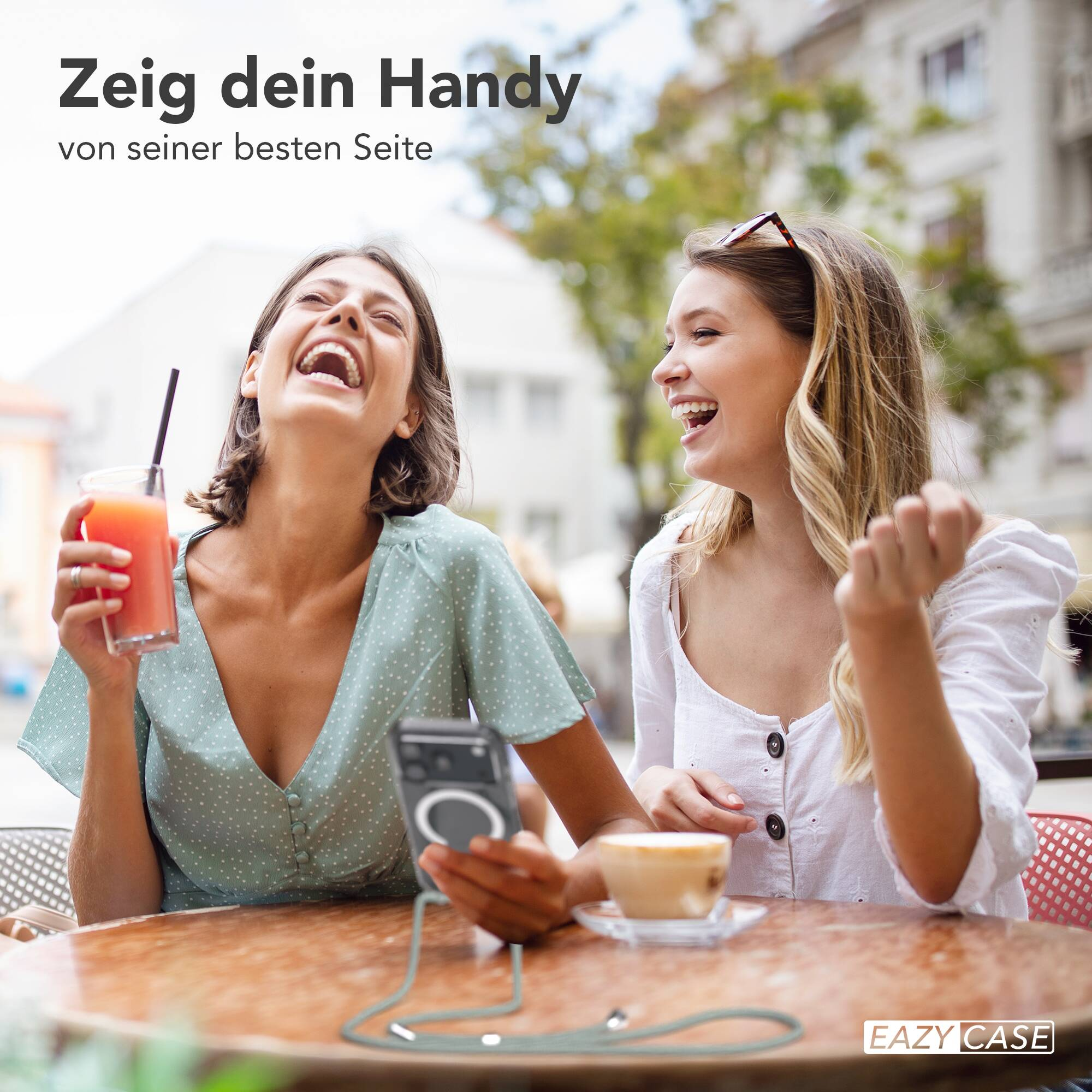 Zwei gut gelaunte Frauen sitzen in einem Straßencafé und lachen herzlich miteinander.