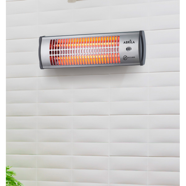 Un calefactor radiante de pared plateado con elementos naranjas brillantes montado en una pared de azulejos blancos.