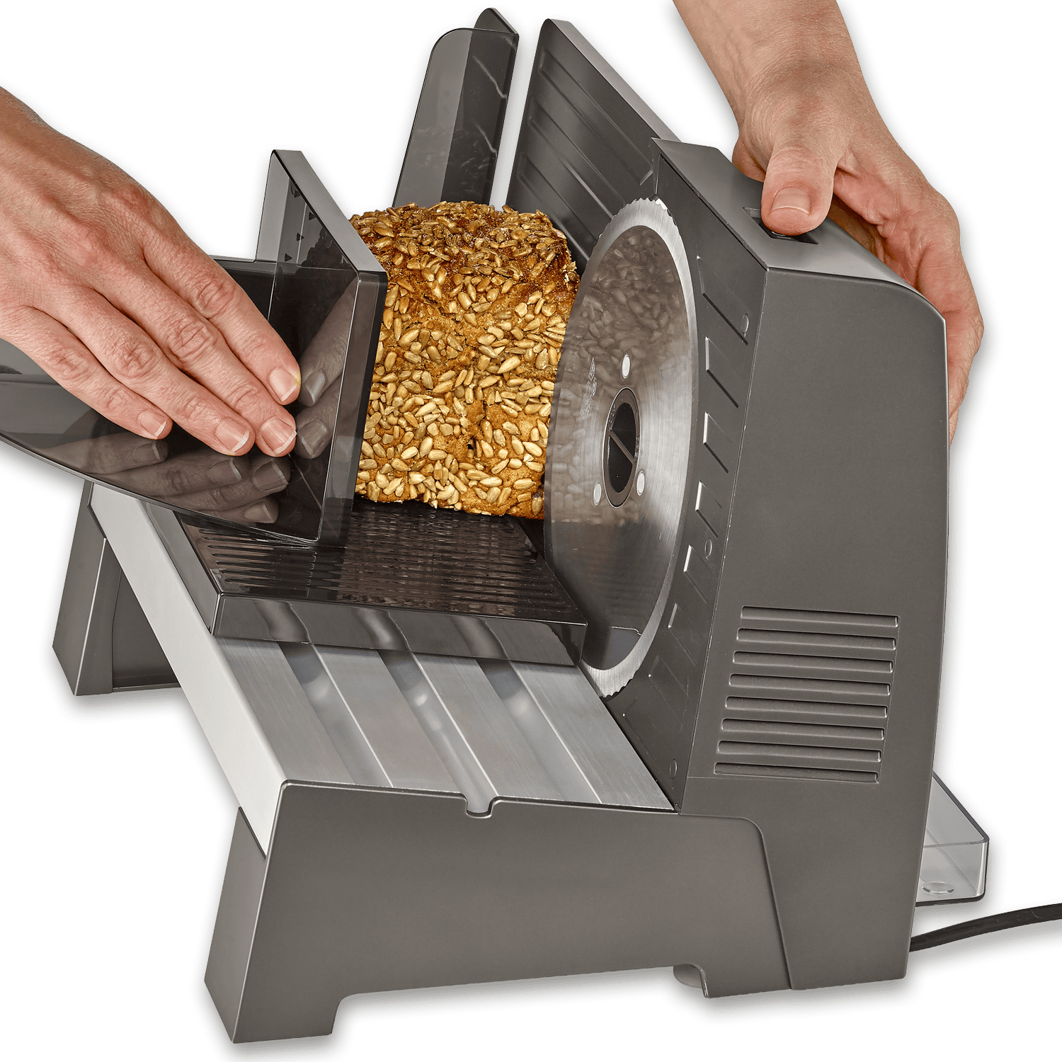 Hände schneiden ein Sonnenblumenkernbrot mit einer elektrischen Brotschneidemaschine.