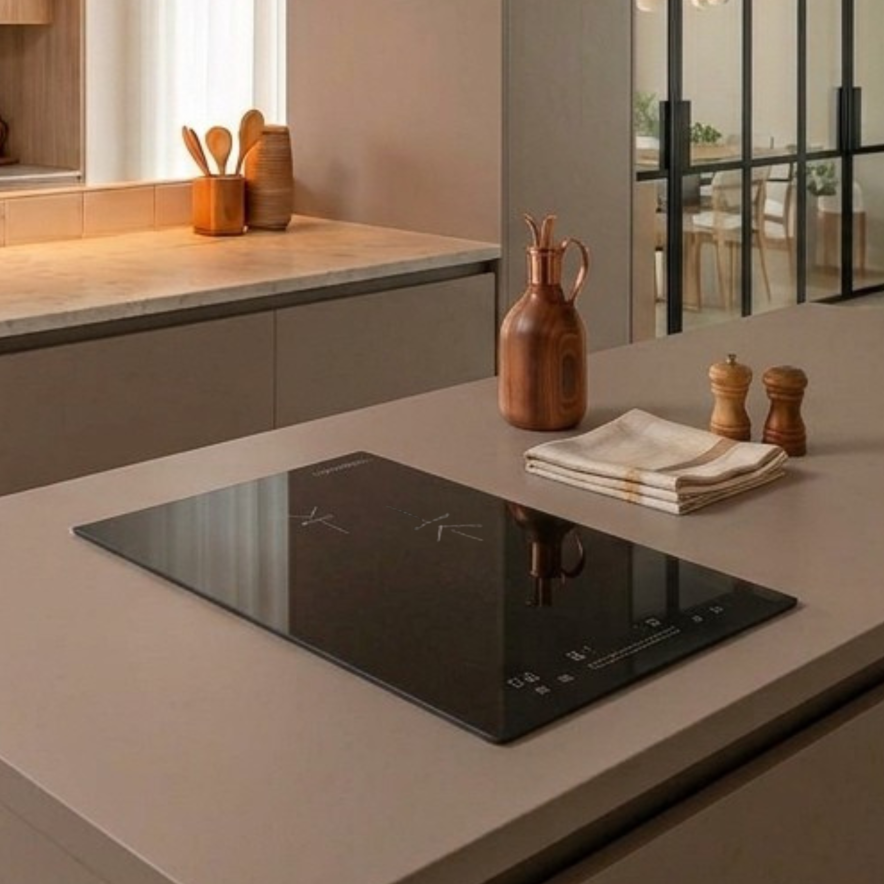 Cucina moderna con piano cottura integrato, oliera in legno, portaspezie e panno piegato sull'isola.