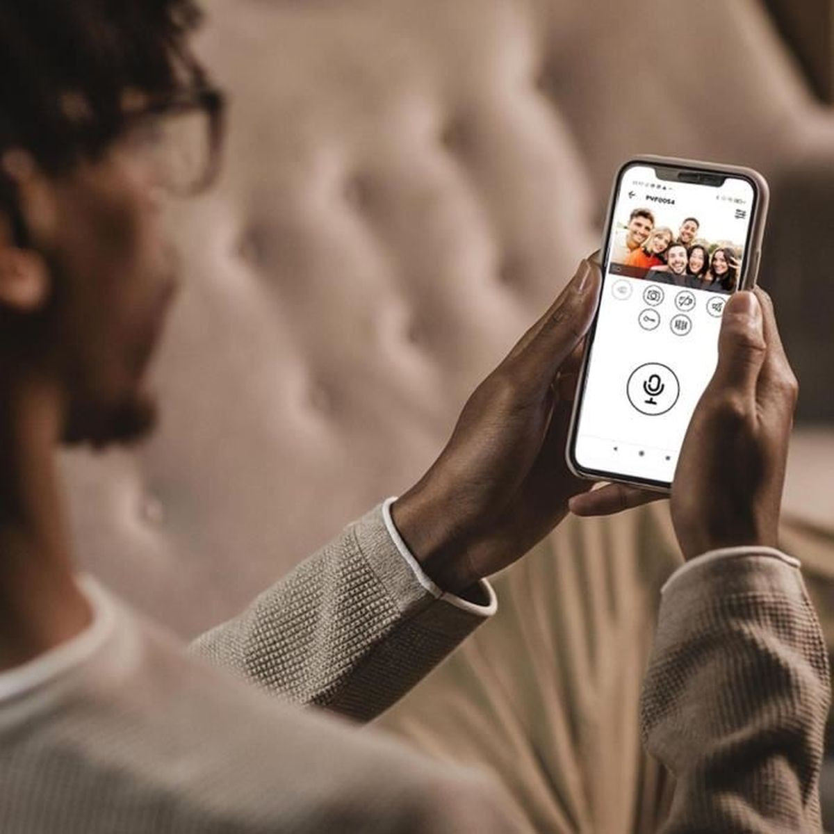 Person hält ein Smartphone, das einen Videoanruf mit einer Gruppe von Menschen zeigt.