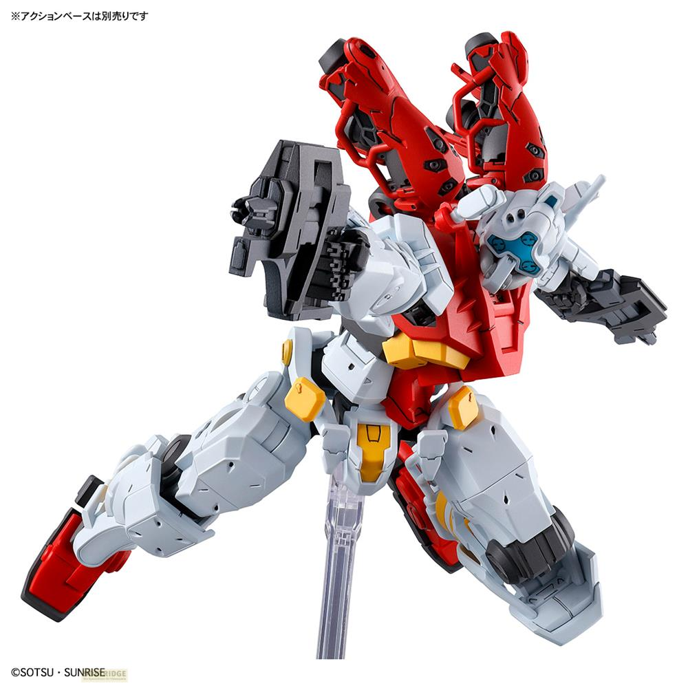 Eine rot, weiß und gelbe Gundam-Actionfigur in dynamischer Pose mit Waffe auf einem Ständer vor weißem Hintergrund.